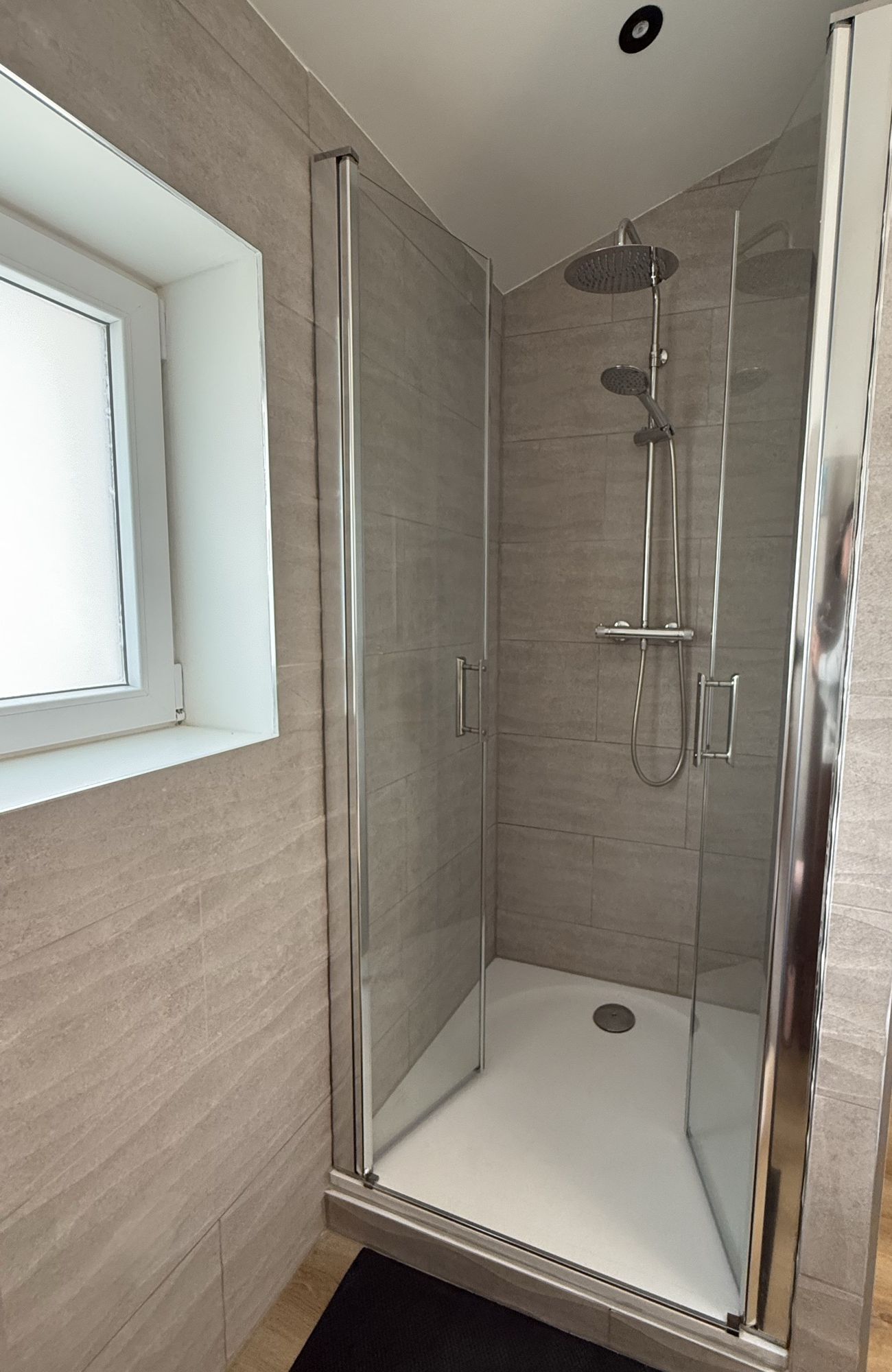 Douche à portes vitrées avec colonne et pommeau de pluie