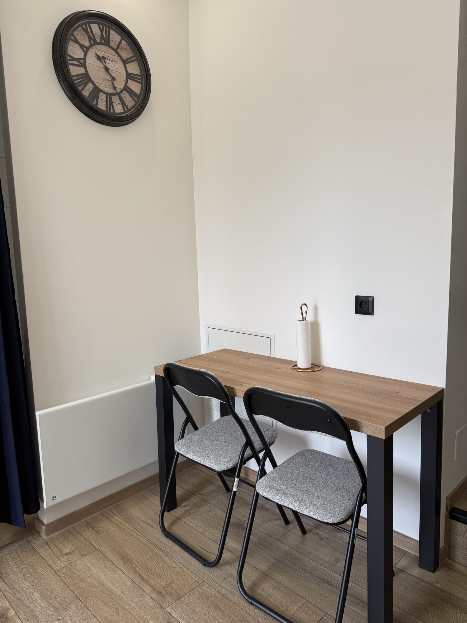 Coin repas : table en bois et deux chaises, horloge murale